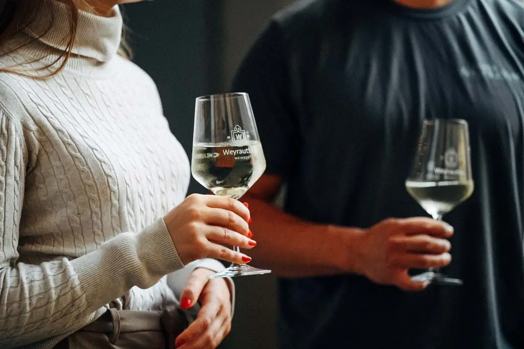 Leute halten Weingläser mit Aufschrift "Weyrauther Weingut" in der Hand