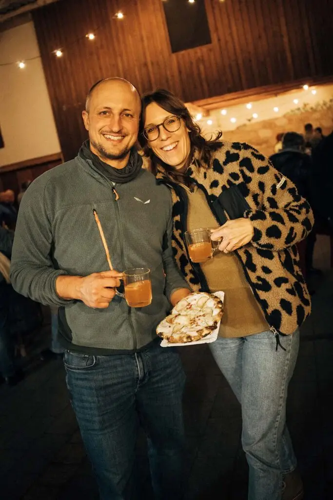 Lachendes Paar mit Heißgetränken und Pinza beim Winterfest 2025 im Weingut Weyrauther
